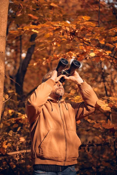 Kuşları ve diğer hayvanları dürbünle gözlemleyen amatör kuş gözlemcisi..