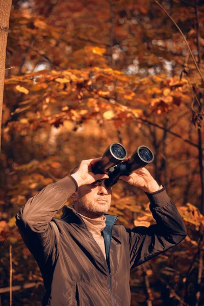 Kuşları ve diğer hayvanları dürbünle gözlemleyen amatör kuş gözlemcisi..