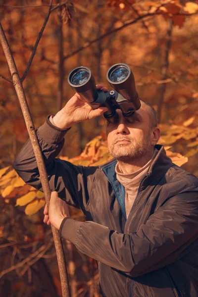 Kuşları ve diğer hayvanları dürbünle gözlemleyen amatör kuş gözlemcisi..