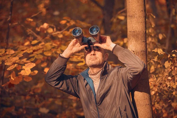 Kuşları ve diğer hayvanları dürbünle gözlemleyen amatör kuş gözlemcisi..