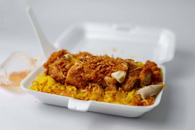 Köpük kutusundaki Tavuk Biryani adlı yiyeceğin yakın plan fotoğrafı.