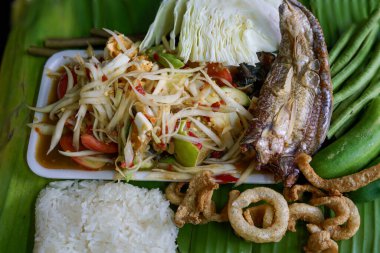 Isan Thai yemeği Papaya salatası, balık turşusu, tuzlu yumurta çeşitli makineler yeşil muz yaprağı arka planı
