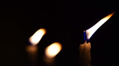 Geceleri mum yakan insanların el görüntüleri.