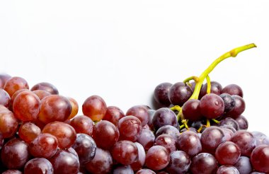 Beyaz zemin üzerinde su damlacıkları olan kırmızı çekirdeksiz üzümlere yakın çekim.