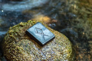 Taş ve akşam nehir arka plan üzerinde İskandinav rune Othala (Odal). Erkek olgunluğu, aile, ev, gelenek, mülk koruma. Rün yüce İskandinav Tanrısı Odin ile ilişkilidir.