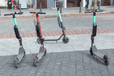 Şehir merkezinde yol tarafından park edilmiş dört elektrikli scooter var..