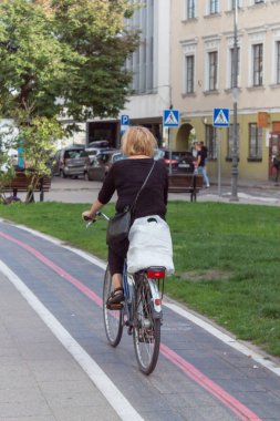 Bir kadın şehir merkezinde bisiklet yolunda bisiklete biniyor..