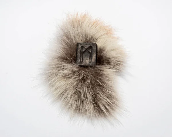 Norse rune Mannaz, isolated on fur and white background. Humanity, the development of the best human qualities. Self-realization. Work with human resources.