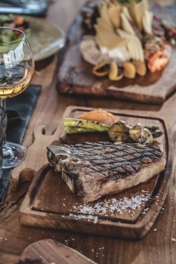 Izgara sığır t-kemik şarap ve ızgara sebze ile ahşap servis tabağında servis 