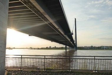 Köprünün altından gün batımı ışığı geliyor. Düsseldorf Almanya, Ren nehri.