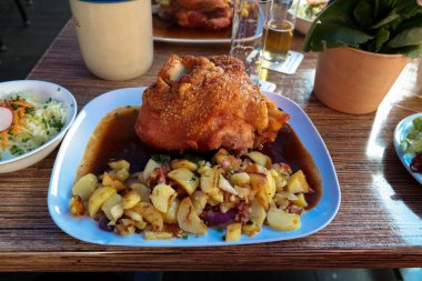 Patates ve salatalı kızarmış domuz eti tabağında. Her gün masada Alman yemeği.