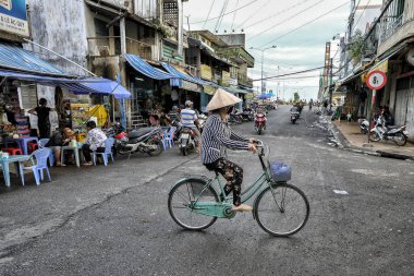 My Tho, Vietnam - 9 Ağustos: My Tho, Vietnam'da 9 Ağustos 2018'de bisiklete binen geleneksel non la konik şapka giyen bir kadın.