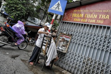 Hanoi, Vietnam - 28 Ağustos: Berber 28 Ağustos 2018'de Hanoi'de sokakta bir adamı tıraş ediyor.
