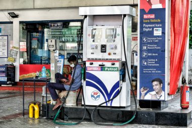 Kochi, India - May 2020: A gas station worker looks at his cell phone while wearing a mask on May 31, 2020 in Kochi, Kerala, India. clipart
