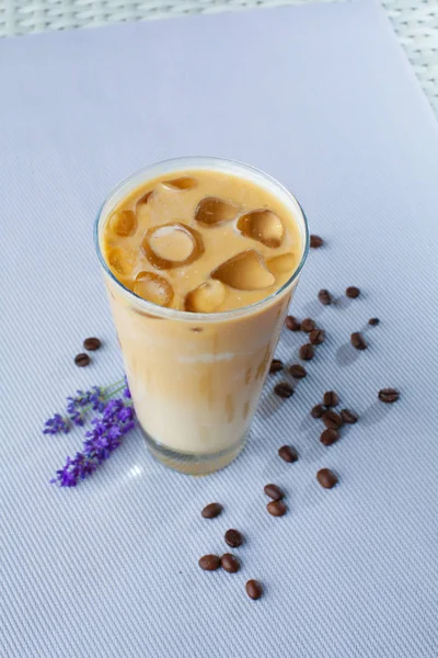 Iced coffee, sprig of lavender and cocoa beans on a gray background