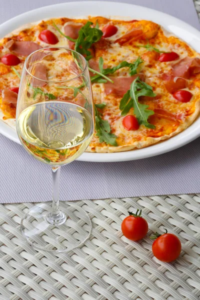 Pizza with ham on a plate and a glass of wine