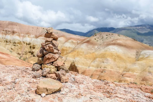 A cairn of stones on Valley of Mars landscapes in the Altai Mountains. Rainbow mountains. Ground con.tains mercury, that`s why it looks like Mars planet. Altai. Nature of Siberia, Russia