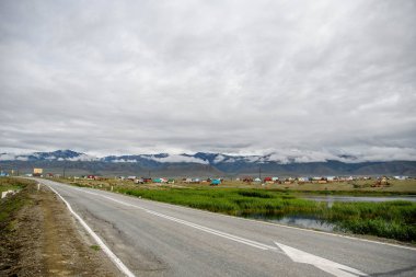 Güzel dağlar manzarası. Dağda küçük bir Altay köyünde dik yol, sis dağ zirveleri, kasvetli gökyüzü bulutlu