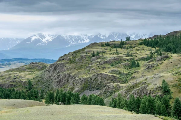 Amazing landscape. The majestic and proud mountains of Altai. Mountains covered with snow, Aktru glacier under a gloomy sky with gray clouds