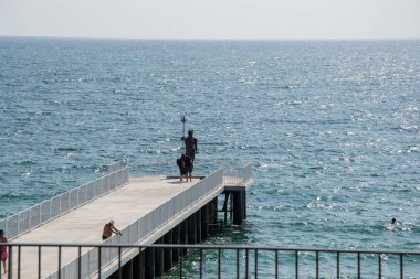 Poseidon, mavi deniz ve gökyüzü, St Konstantin ve Elena, Varna, Bulgaristan heykeli ile bir iskelede insanlar