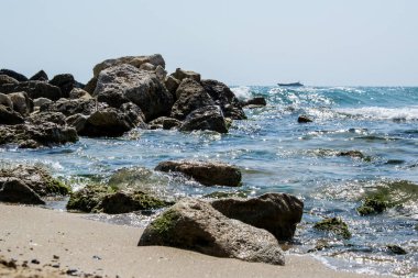 Güzel vahşi sahil manzarası, güneşli bir gün, kayalıklara vuran su dalgaları, yaz manzarası.