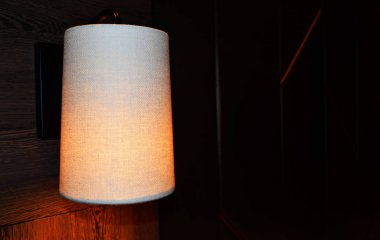 Ahşap yüzeyde kumaş abajurlu Parlak duvar lambası, kahverengi arka plan 