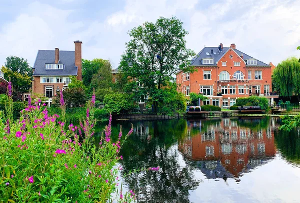Beautiful houses along the river in Vondelpark Amsterdam, Netherlands. House reflection in the water. Home in a river. Private cottage or summer house.
