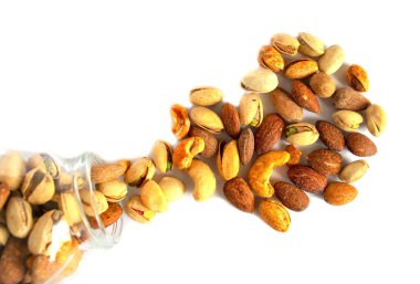 Beyaz arka plan üzerinde izole kavanozdan karışık fındık. Sağlıklı atıştırmalık ve yiyecek. Tuzlu ve baharatlı antep fıstığı, kaju ve badem. Üst görünüm, düz yatıyordu. Sağlıklı fındık büyük çeşitli.