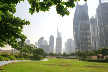 Dubai / Uae - 15 Ekim 2019: Jumeirah Lakes Towers gökdelenleri ve park manzarası. Jlt 'deki konut binaları. Yaprakların ve sislerin arasında. 