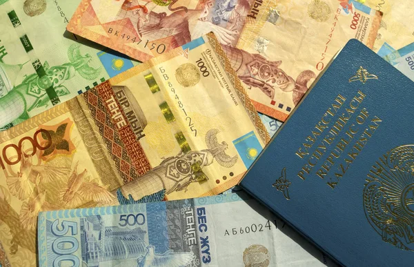 Dubai / BAE - 10 Haziran 2020: Pasaportlu Kazakistan ulusal para biriminin arka planı, karışık banknotların üst görünümü. Kz kağıt para ve Kazak uluslararası pasaport