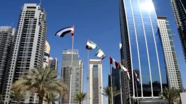 BAE bayraklı Dubai gökdelenlerinin manzarası. Mavi arka planda Birleşik Arap Emirlikleri bayrakları dalgalanıyor. Ulusal gün. Birçok BAE bayrağı 