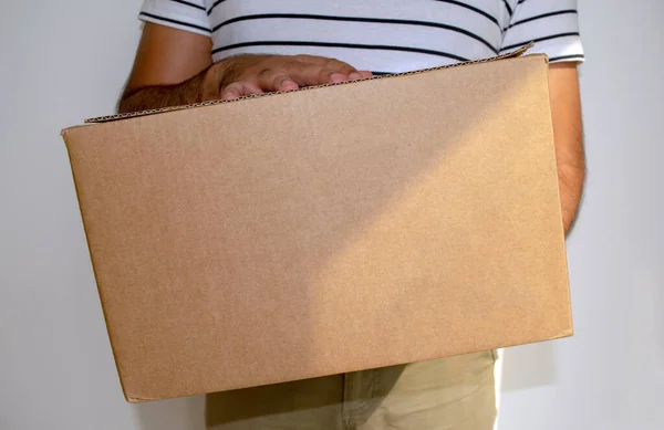 Der Mann hält ein Pappkarton-Paket in der Hand. Online-Einkauf und Express-Lieferung. Zusteller. — Stockfoto