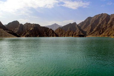 Arkasında kayalık Hajar Dağları olan güzel, koyu yeşil Hatta Gölü. Hatta barajının BAE 'deki görüntüsü. Orta Doğu 'da resim gibi bir doğa.. 