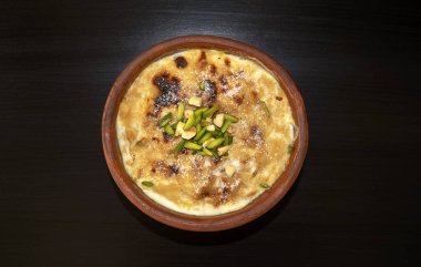 Geleneksel Arapça, doğu tatlıları Om Ali. Üst Manzara. Koyu ahşap masada kahverengi bir kasede mısır ekmekli puding. Üst Manzara. Mısır tatlı tatlı tatlı tatlı