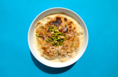 Geleneksel Arapça, doğulu tatlı Om Ali. Üst Manzara. Mavi arka planda beyaz bir kasede mısır ekmekli puding. Üst Manzara. Mısır tatlı tatlı tatlı tatlı