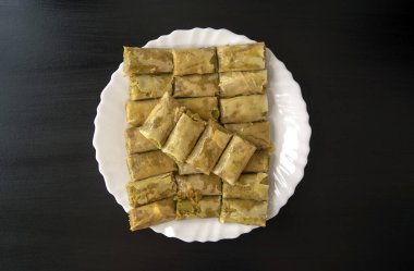 Geleneksel Türkçe, Arapça, ortadoğu baklavası. Üst Manzara. Siyah ahşap masada beyaz tabakta pişmiş Arap tatlısı. Mini Baklawa 
