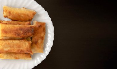 Ünlü geleneksel Orta Doğu, Asya mutfağı. Siyah ahşap arka planda sebzeli börek ve fotokopi alanı. Beyaz tabakta bir sürü börek var. Üst görünüm