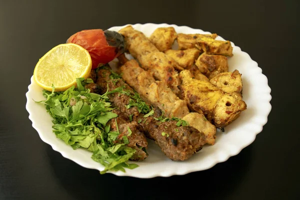 有名な伝統的なアラビア語、トルコ語、イスラエル料理。焼きチキンシャリック、ラム、ビーフコフタケバブ、野菜、暗い木製の背景に白いプレート上のレモン、閉じます。カフタケバブ — ストック写真