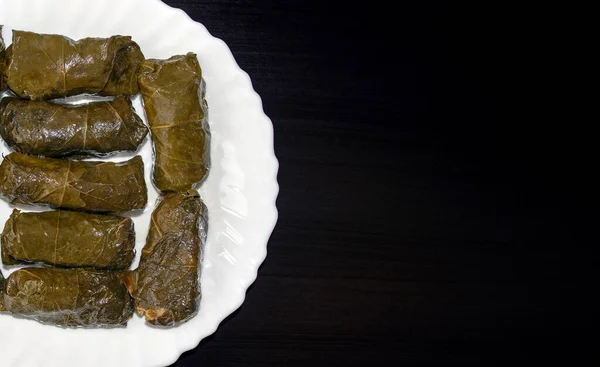 Stuffed Grape leaves on white plate on dark wooden background with copy space. Famous traditional Middle East, Turkish, Asian cuisine. Dolma or stuffed vine leaves — Stock Photo, Image