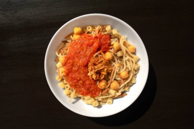 Ünlü geleneksel Arapça, Mısır yemeği Koshari. Ulusal Kushari, siyah ahşap arka planda beyaz bir tabakta. Düz yatış, üst görünüm.