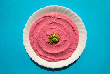 Ünlü geleneksel Arap mutfağı, mavi arka planda beyaz bir tabakta pancar humusu. Arap pancarı ve nar labradoru veya yoğurt. Üst görünüm