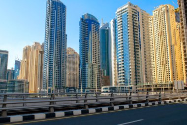 Dubai / BAE - 7 Kasım 2019: Gökyüzü mavi arkaplan üzerinde renkli gökdelenlerle JBR caddesinin görüntüsü. Jumeirah Plaj Konağı ve Marina Yürüyüşü. Dubai yolu ve köprüsü. 