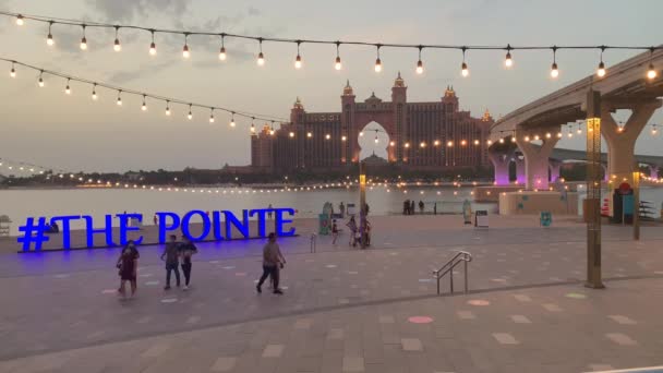 ドバイ アラブ首長国連邦 8月30 2019 日没前にアトランティス パームホテルの景色を望む広場のポイントサイン 観光客や太陽のまぶしさとタイル張りの歩道 — ストック動画