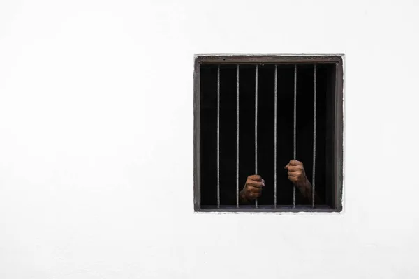 Pencere ve hapishane hücresinin paslı çubuğunda mahkumun elleri