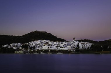 Limanında tekneler ile bir nehrin kıyısında alacakaranlıkta Beyaz şehir