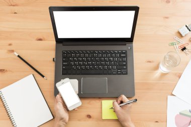 genç kadın çalışan dizüstü bilgisayar el ahşap masada akıllı telefon tutan