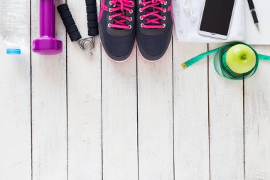 Sağlıklı spor konsepti, spor ayakkabıları, elma, su ve ahşap arka planda akıllı telefon, üst manzara