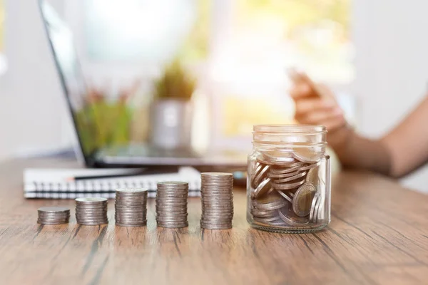 coin stack step on desk with women using the computer.,Saving money and finances concept,