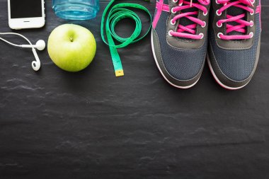 Fitness sağlıklı konsept, spor ayakkabı, elma, su ve siyah arka plan üzerinde akıllı telefon, üst görünüm