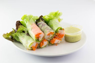 Beyaz arka planda beyaz bir tabakta salata rulo.